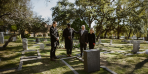 4 people in black clothing at a gravesite