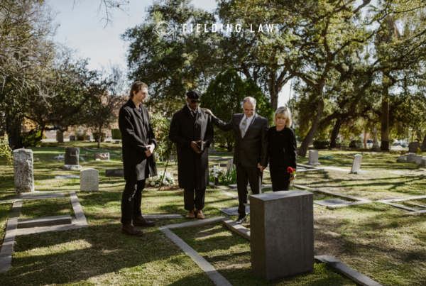 4 people in black clothing at a gravesite