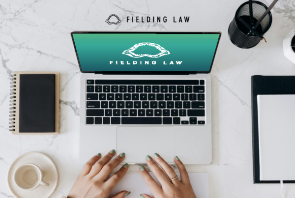 Fielding Law on laptop screen sitting on a desktop with books and small plants