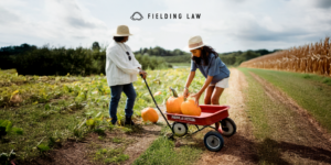 Two people in a pumpkin patch gathering pumpkins into a wagon