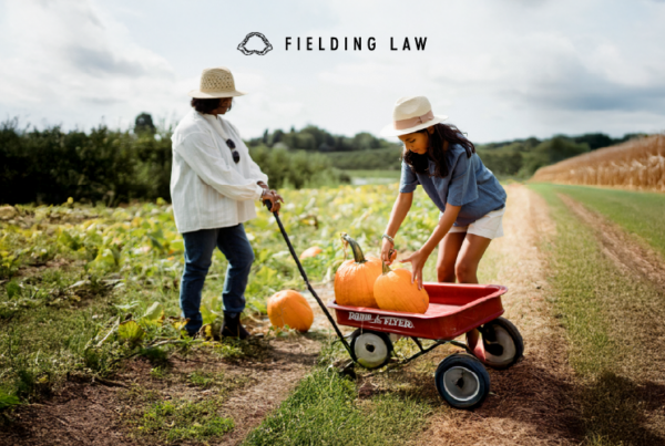 Two people in a pumpkin patch gathering pumpkins into a wagon