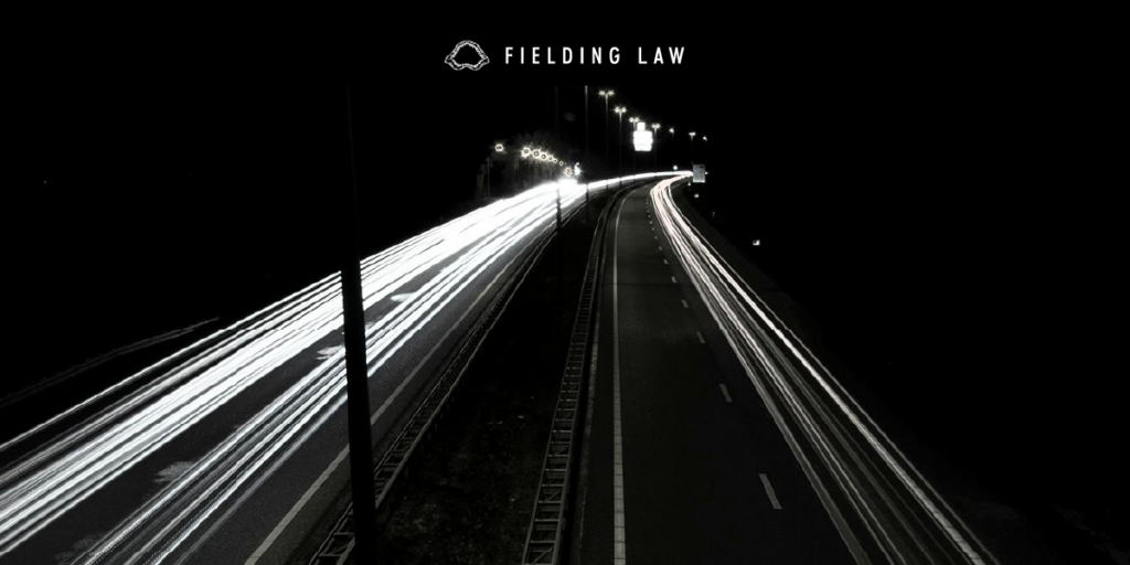 cars driving on a highway at nighttime