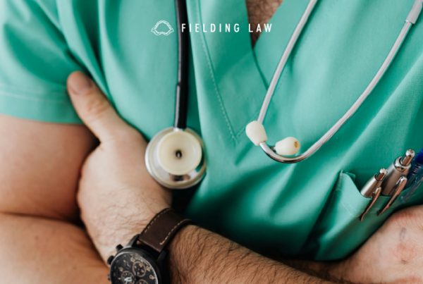 Doctor with stethoscope around neck in green scrubs with arms crossed