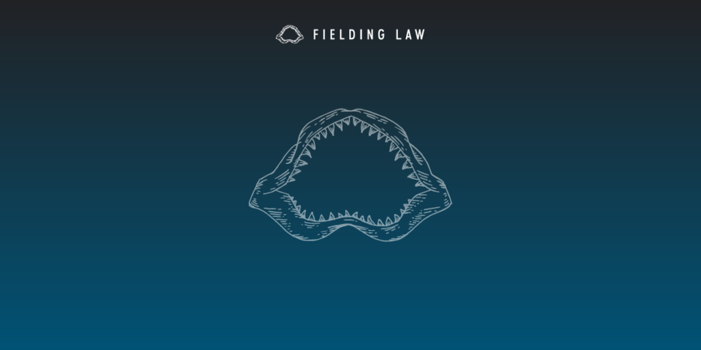 Navy blue gradient background with a Fielding Law Shark Jaw logo