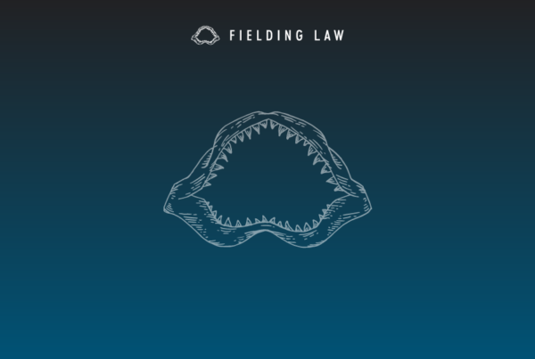 Navy blue gradient background with a Fielding Law Shark Jaw logo