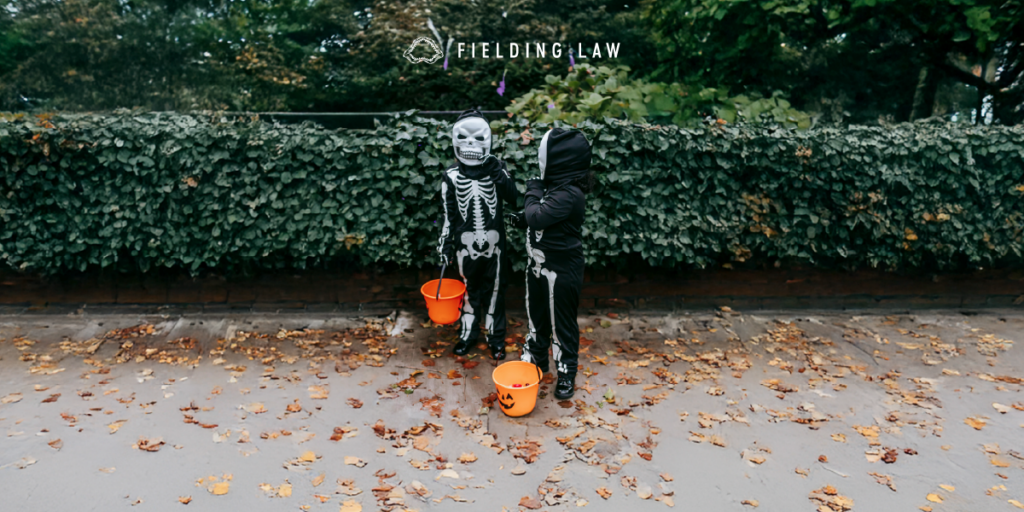 Two Trick-or-Treats on the sidewalk with greenery
