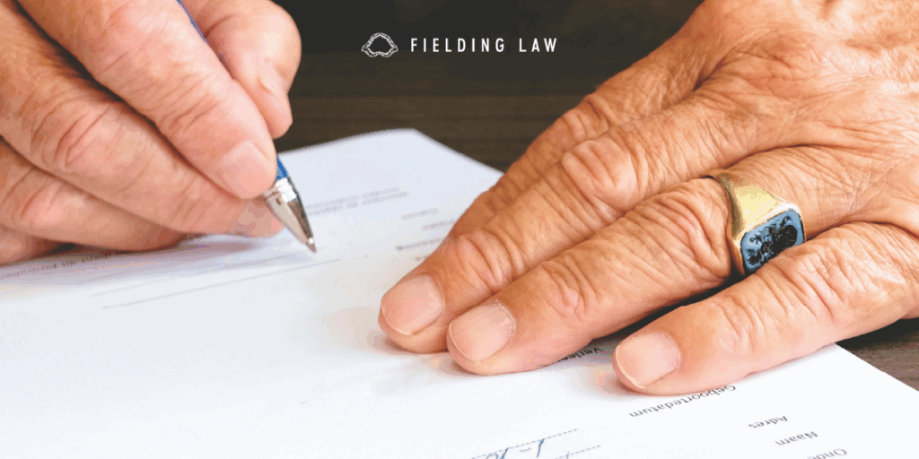 two hands signing a piece of paper