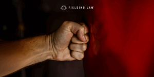 Fist hitting red shiny side of a vehicle