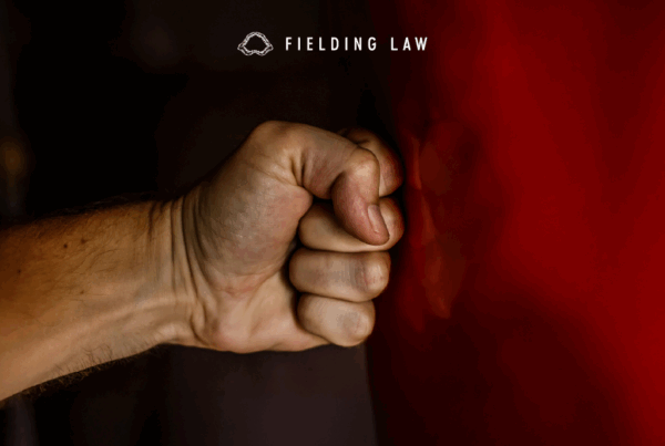 Fist hitting red shiny side of a vehicle