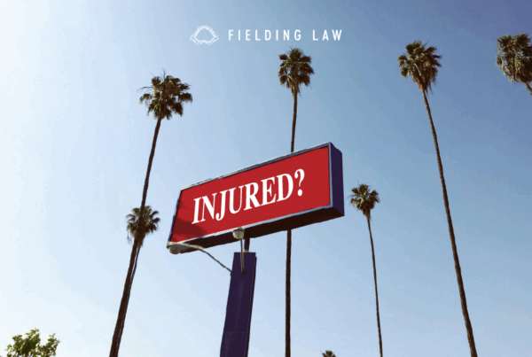 Red billboard that read Injured? with palm trees in the background