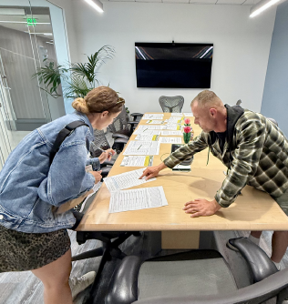woman signing ballot initiative. Signature collector is pointing where to sign