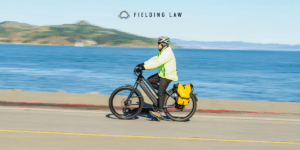 Person on an E-bike driving on a road next to water