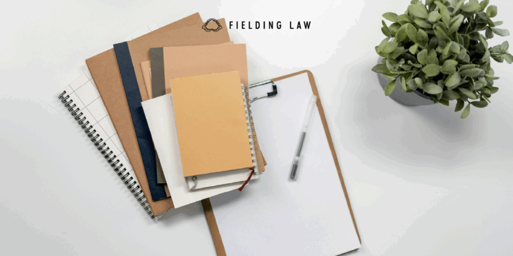 journal and folders with a clipboard and pen on a desk.